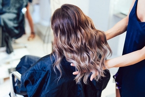 Brunette woman with stunning blonde ombre hair sitting in a chair after a haircut